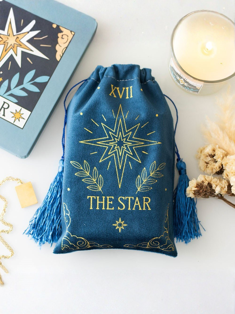 Blue drawstring bag with 'The Star' design on a white surface with tarot cards and candle.