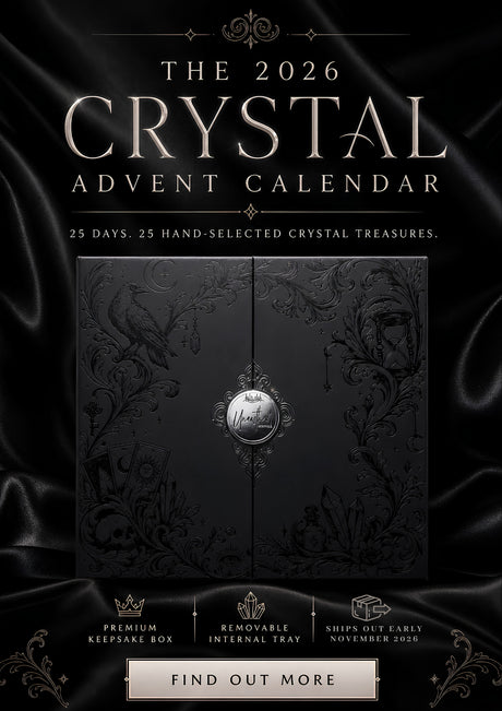 The 2026 Crystal Advent Calendar cover shown against a black satin background. The central product is a dark ornate box with floral engravings and a silver medallion, with large metallic text reading 'THE 2026 CRYSTAL ADVENT CALENDAR' and smaller tagline text below.
