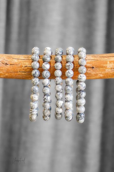 Set of beaded bracelets on a wooden stick with a gray curtain background