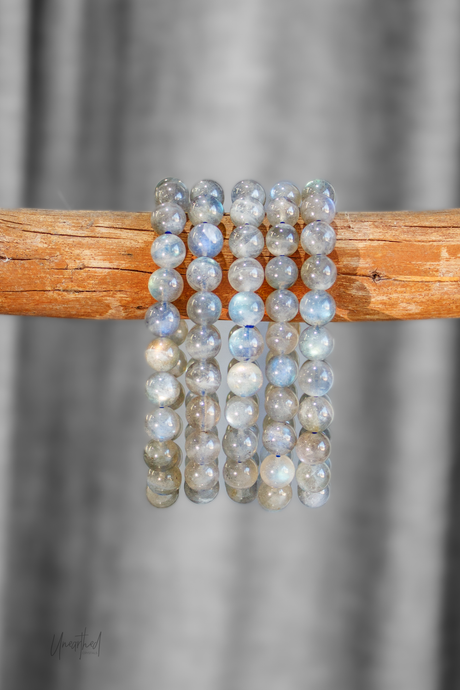 Labradorite beaded bracelets on a wooden stick with a gray background