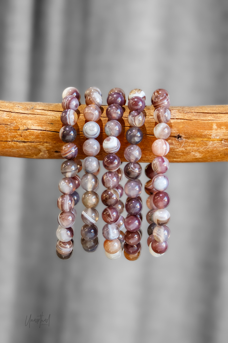 Set of beaded bracelets on a wooden stick with a blurred gray background