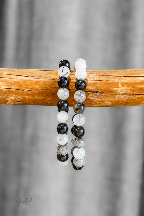 Two beaded bracelets on a wooden stick with a gray background