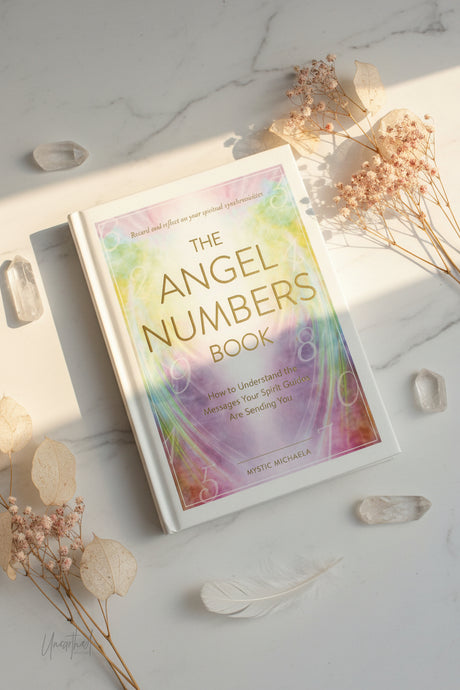 Book titled 'The Angel Numbers Book' on a light surface with decorative elements