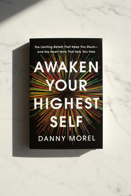 Book titled 'Awaken Your Highest Self' by Danny Morel on a marble surface