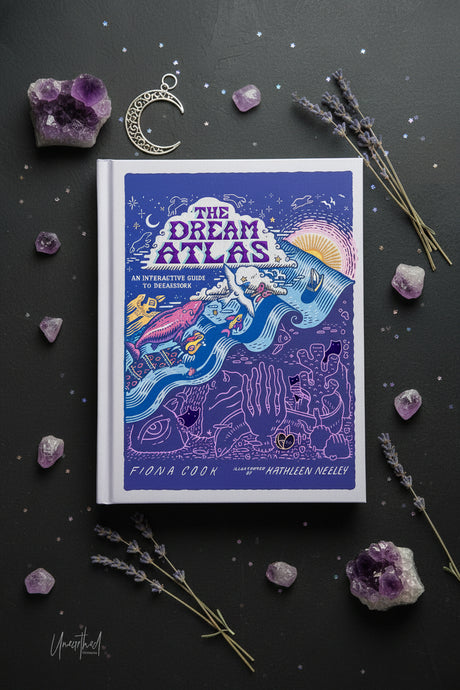 The Dream Atlas: An Interactive Guide to Dreaming book by Fiona Coon and Kathleen Neeley, featuring a colorful illustrated cover with a blue and purple background and whimsical dreamlike scenes.