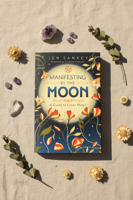 Book titled 'Manifesting by the Moon' by Jen Sankey on a textured surface with decorative elements.