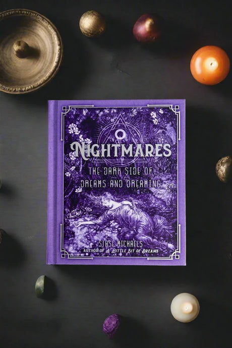 Purple book titled 'Nightmares' on a dark surface with mystical objects.