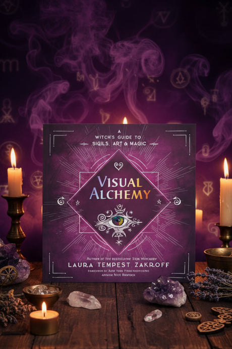 Book titled 'Visual Alchemy' with candles and mystical elements on a dark background