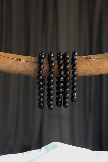 Wooden stick with black Shungite beads against a dark background