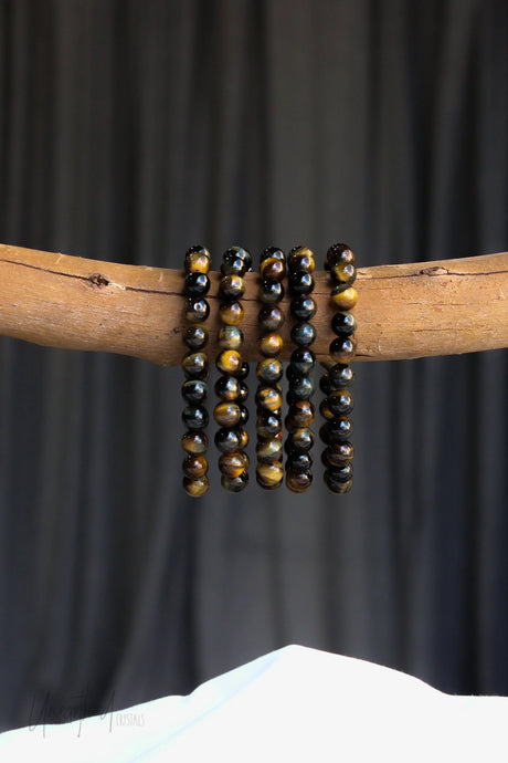 Set of Blue Tiger Eye beaded bracelets on a wooden stick against a dark background