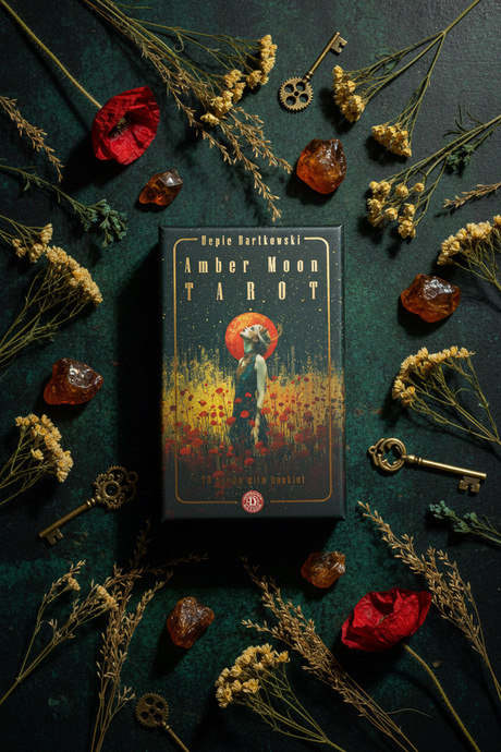 Amber Moon Tarot book surrounded by dried flowers and keys on a dark surface