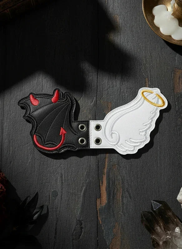 Decorative boot accessories with angel and devil designs on a dark surface