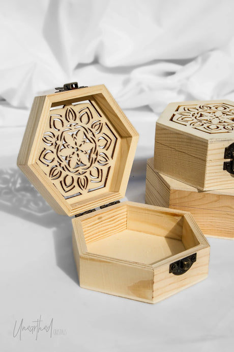 Hexagonal wooden box with intricate cut-out design on a light background