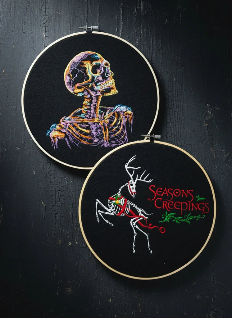 Two embroidered hoops with skeleton and deer designs on black fabric.