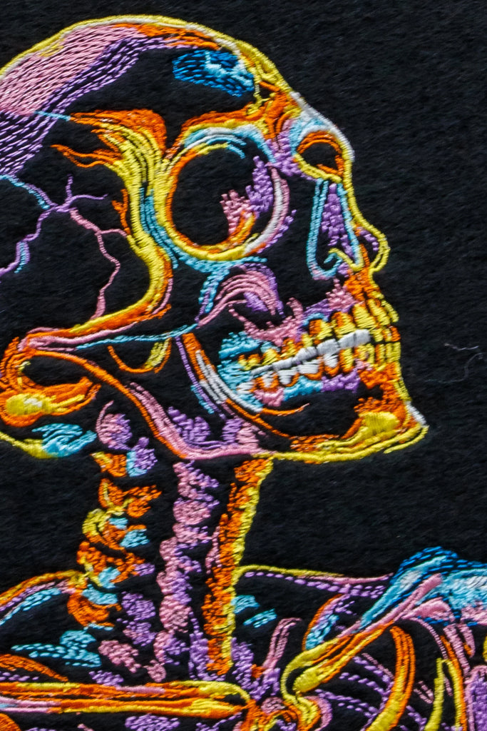 Colorful embroidered skeleton design on black fabric