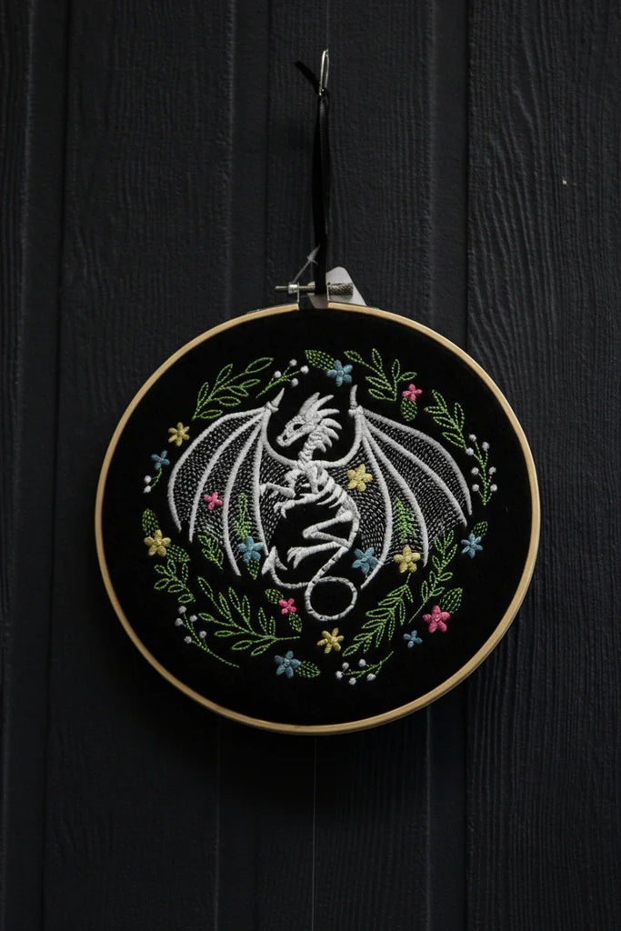 Embroidery hoop with floral and butterfly design on a dark wooden background