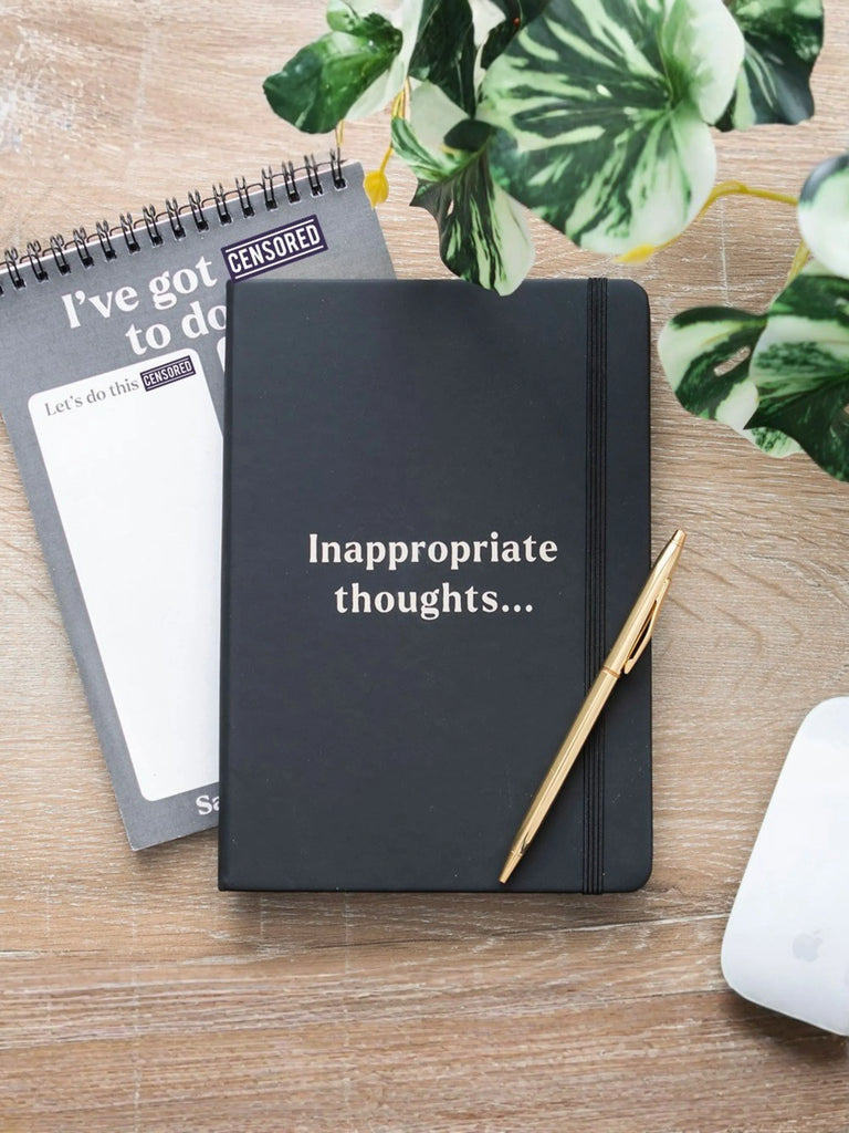 Black notebook with 'Inappropriate thoughts...' text on a wooden surface with a pen and notepad.