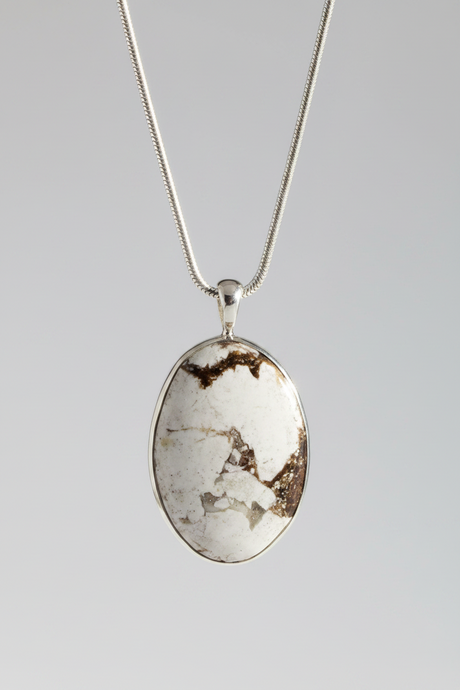 An oval pendant necklace featuring a white and brown marbled stone in a silver bezel setting, suspended from a silver chain against a neutral gray background.