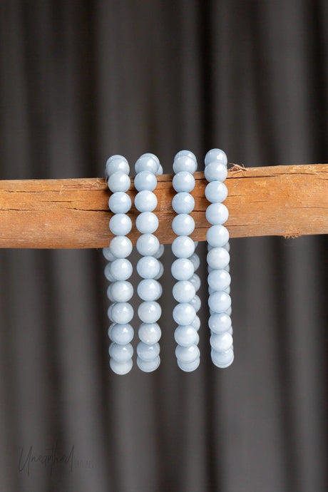 Angelite crystal bead strands in soft blue, displayed on a wooden rod