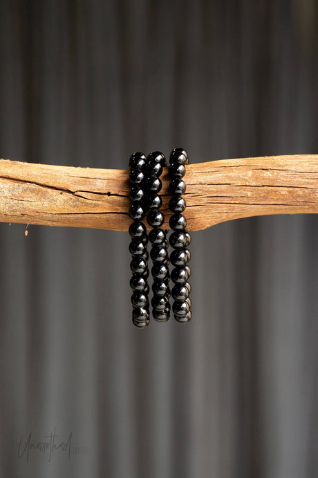 Black Tourmaline beaded bracelets on a wooden branch with a dark background