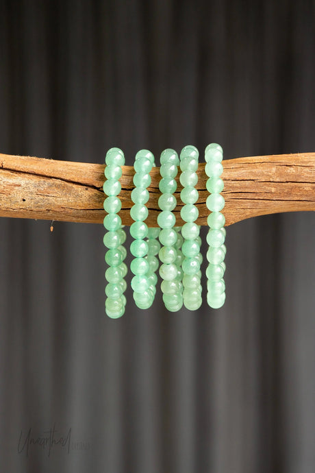 Green Aventurine Beaded Bracelets on a wooden stick against a dark background