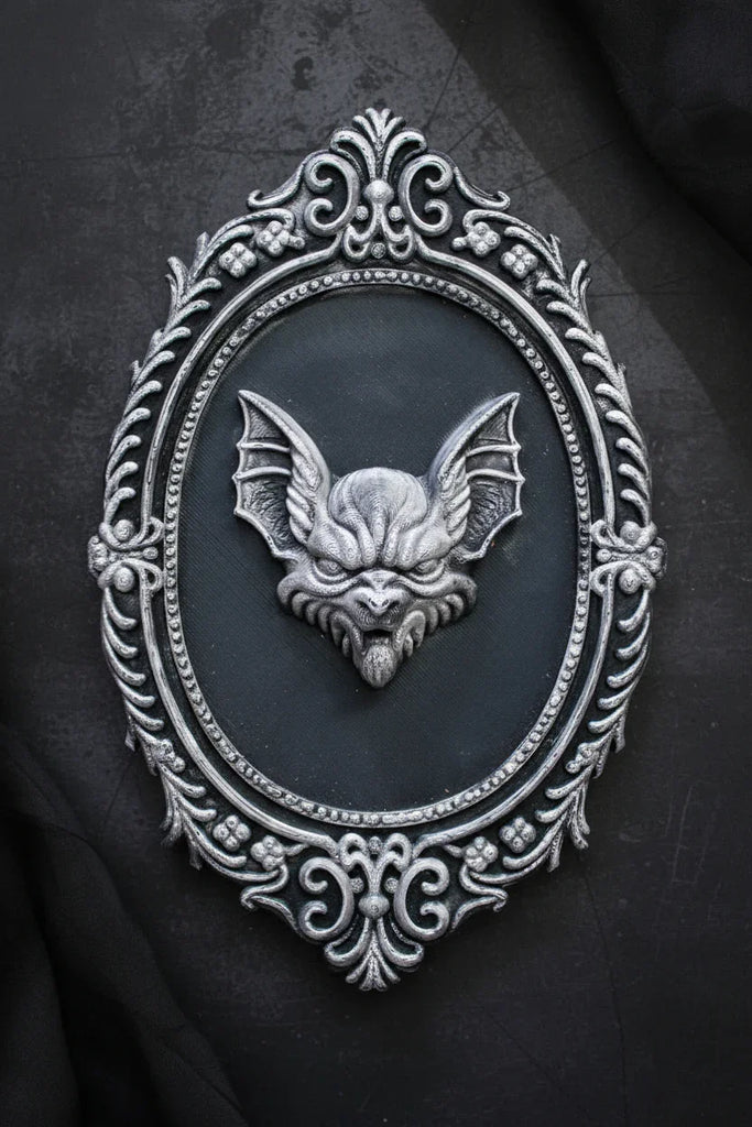 Decorative wall art with a bat design in an ornate frame.