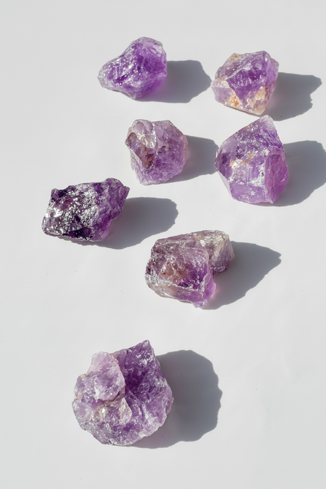 Purple amethyst crystal rocks on a light gray background