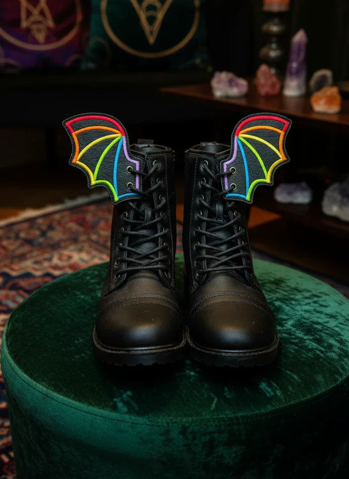 Black boots with rainbow bat wings on a green surface, with a mystical background.