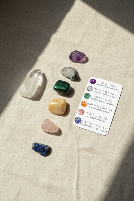 Collection of colorful crystals on a beige fabric surface with a label identifying each stone.