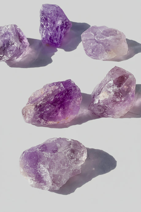 Purple amethyst crystal rocks on a white background