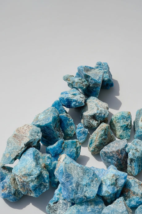 Blue Apatite mineral rocks on a light gray background