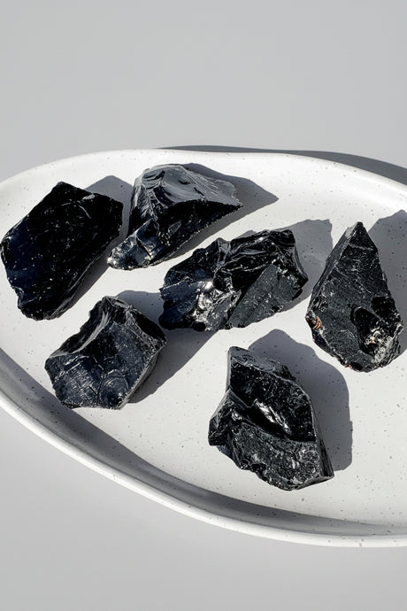 Black Obsidian raw stones on a white plate