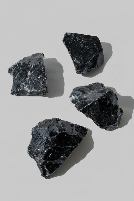 Four Black Obsidian rocks on a light gray background