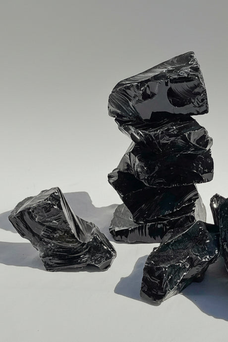 Stack of dark, rough-textured stones on a light gray background