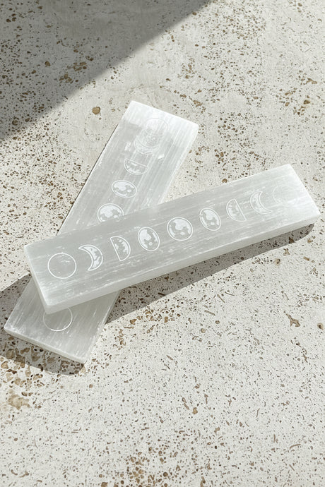 Selenite rods with moon phase carvings on a textured surface